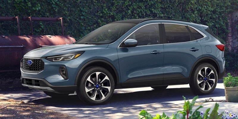 A blue-grey Ford Escape SUV is parked outdoors in a garden setting.