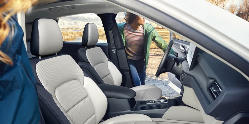 The interior of a car, showing the two-tone front seats and two people getting in